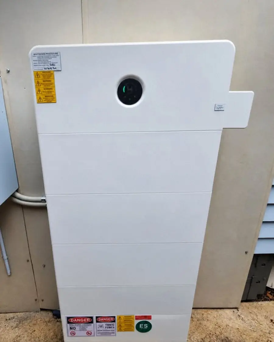A white home battery mounted on an outside wall